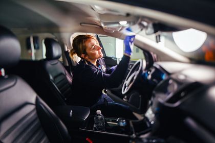 A focused employee wearing gloves carefully inspects the interior of a vehicle